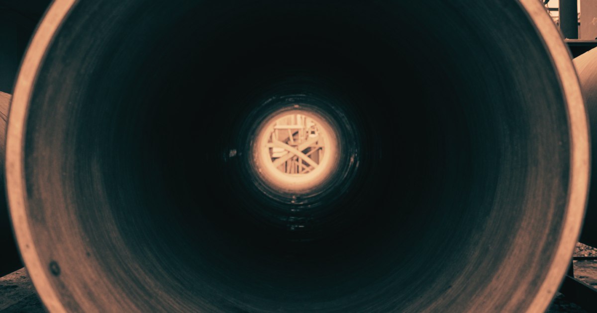 An empty industrial pipe shot looking directly into the open end, circular frame within frame, dark interior