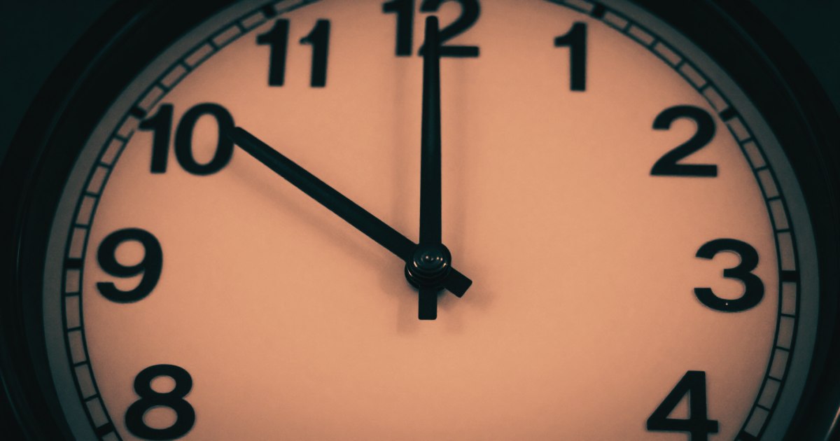 A clock face shot from directly in front, extreme close-up, hands at an unusual position