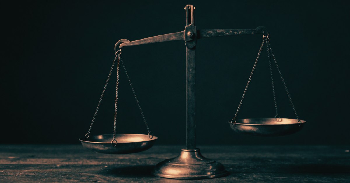 An old brass balance scale, one side visibly lower than the other, dark background