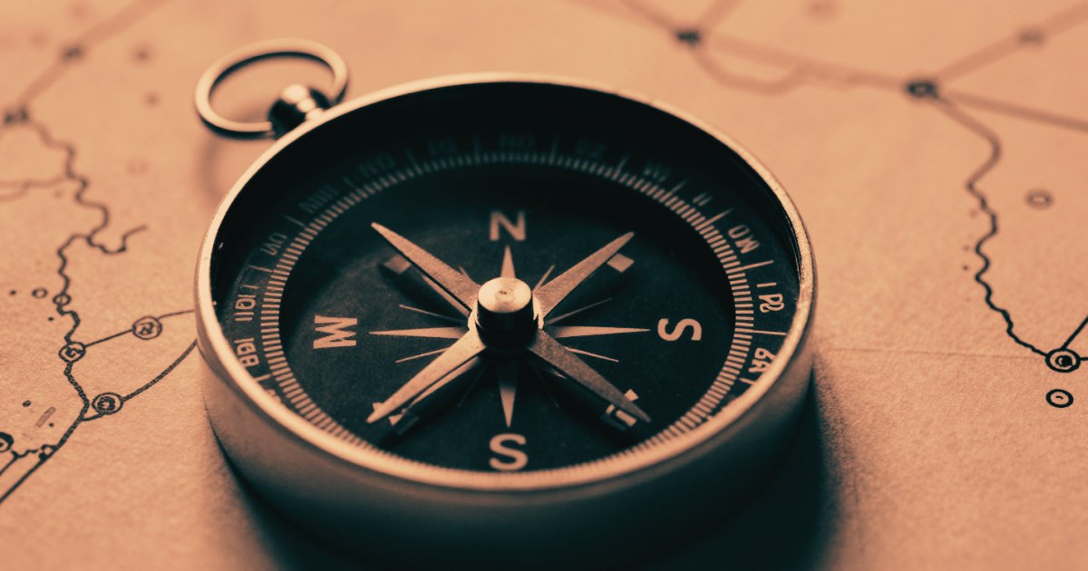 A compass on a blank chart, close crop from above, needle pointing clearly in one direction